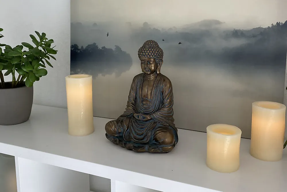Buddha statue between candles on a studio shelf at Serenity Hot Yoga