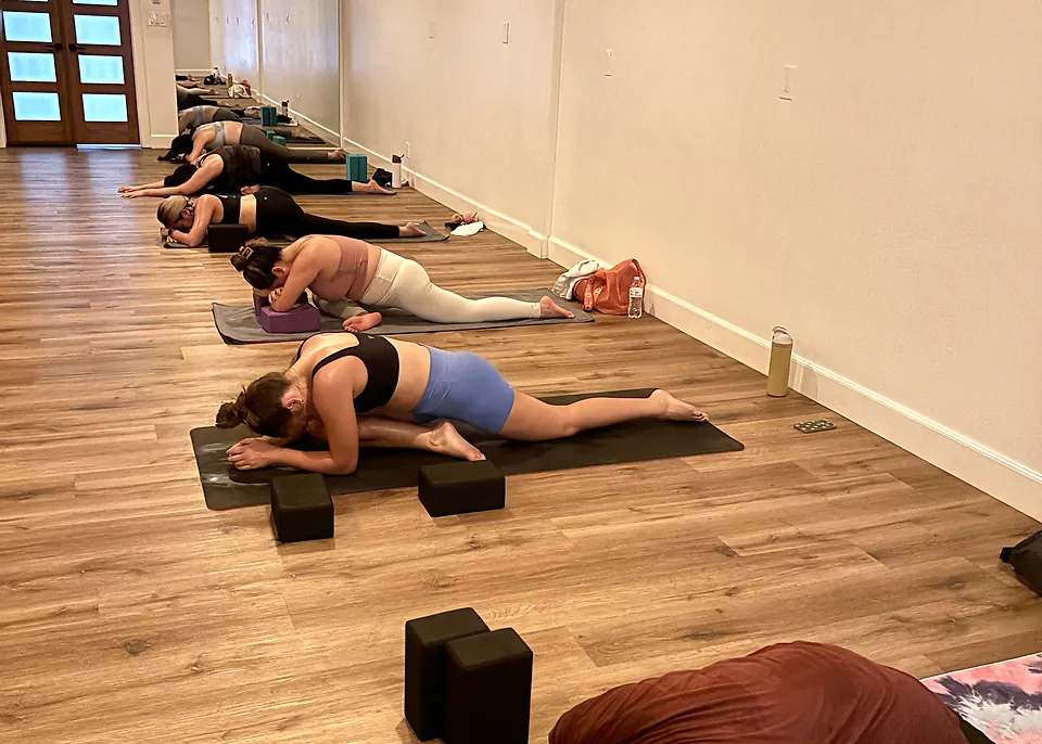 Deep Stretch Yoga students folding forward in pigeon pose at Serenity Hot Yoga
